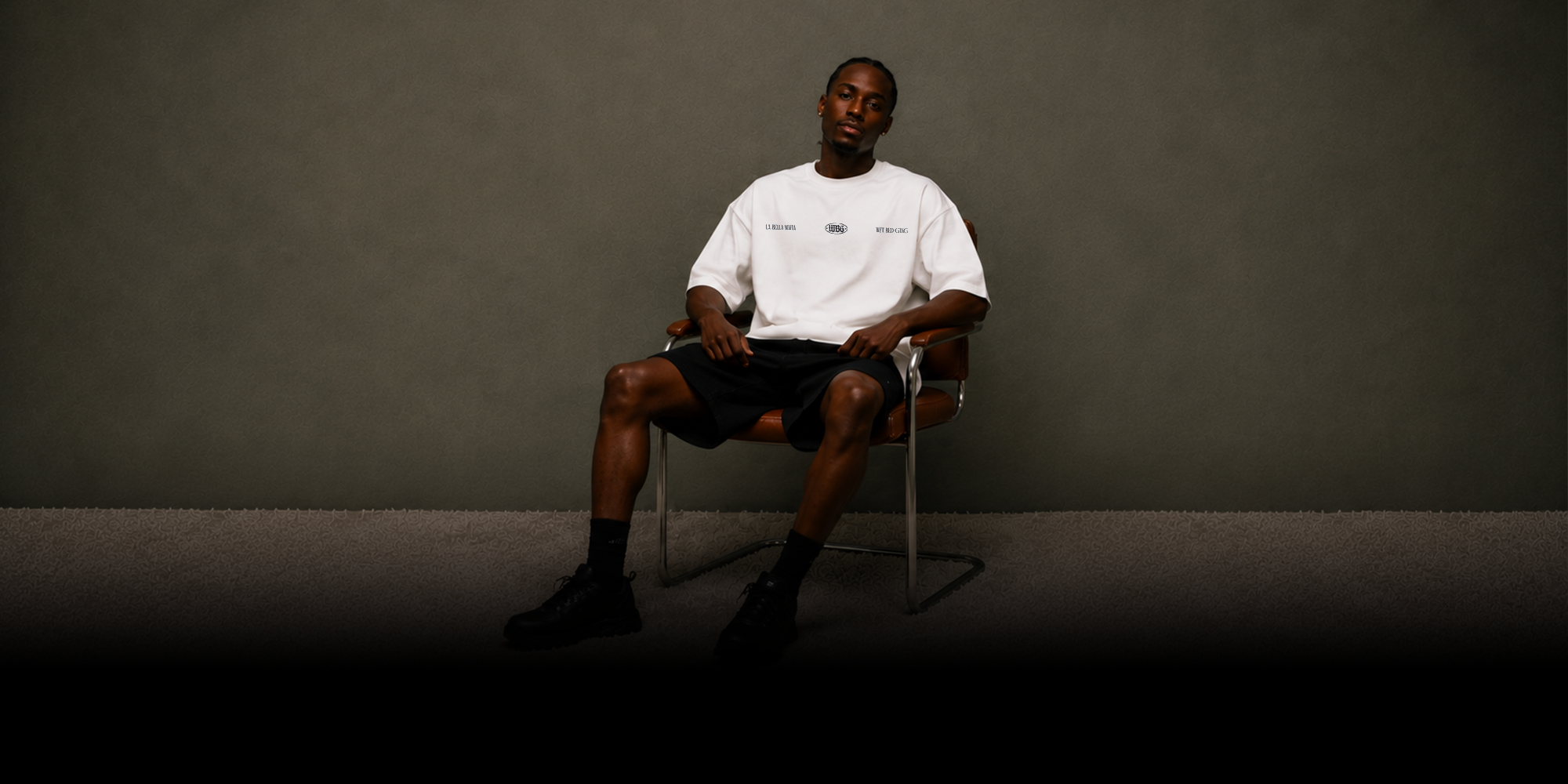 Wet Bed Gang — model seated wearing the white La Bella Mafia T-shirt